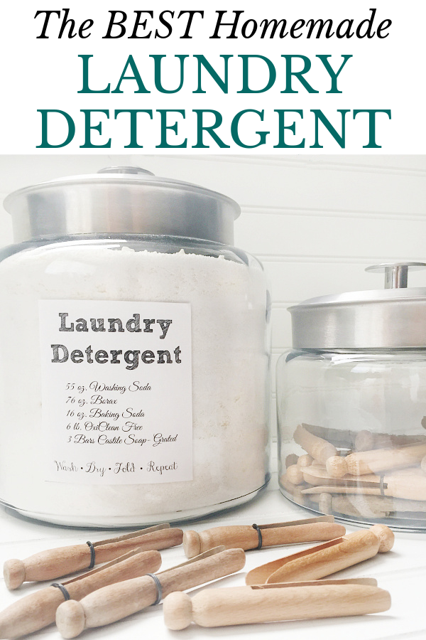 Homemade laundry detergent powder in a large glass canister surrounded by wood clothes pins