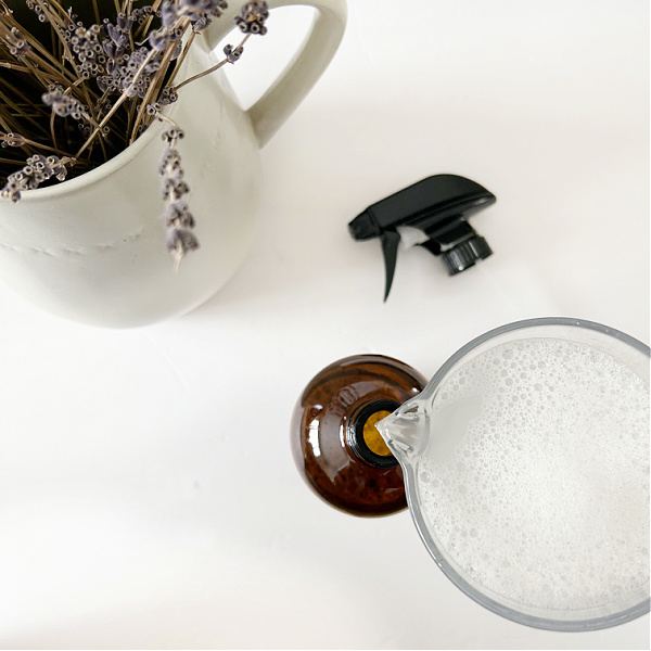 Pouring cleaner into an amber glass spray bottle