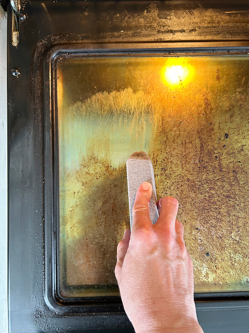 Cleaning oven door with a pumice stone