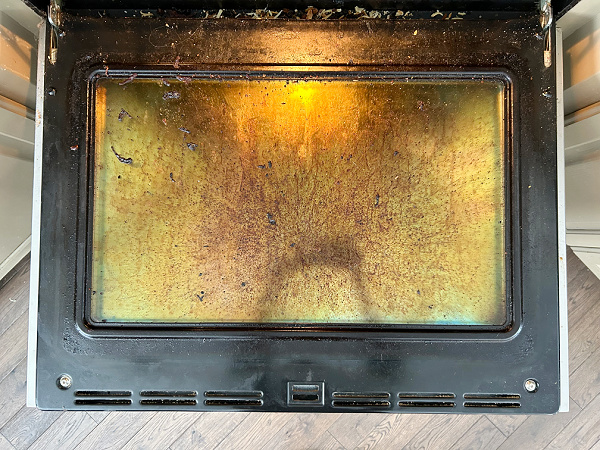 Dirty oven door caked with burnt-on food