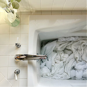 White sheets being stripped in tub full of water