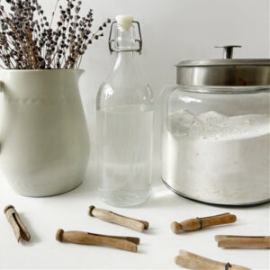 Natural homemade fabric softener next to a container of homemade laundry detergent