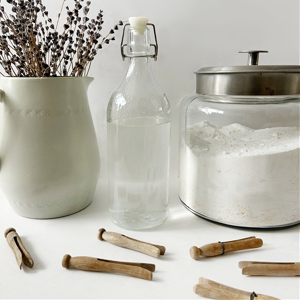 Natural homemade fabric softener next to a container of homemade laundry detergent
